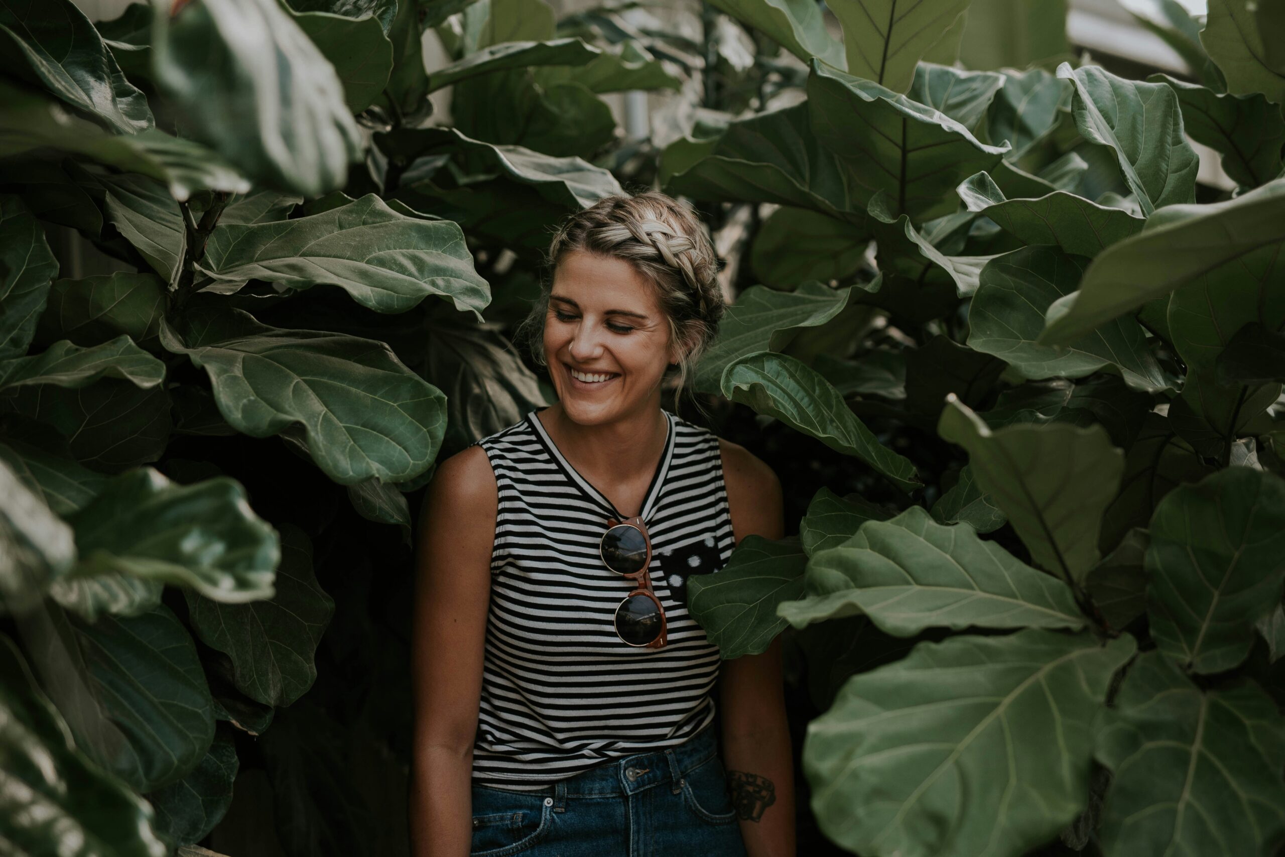 Smiling woman surrounded by lush green leaves, symbolizing personal growth, connection, and renewal through individual therapy at Heartsprout Therapy in Toronto and Vancouver.