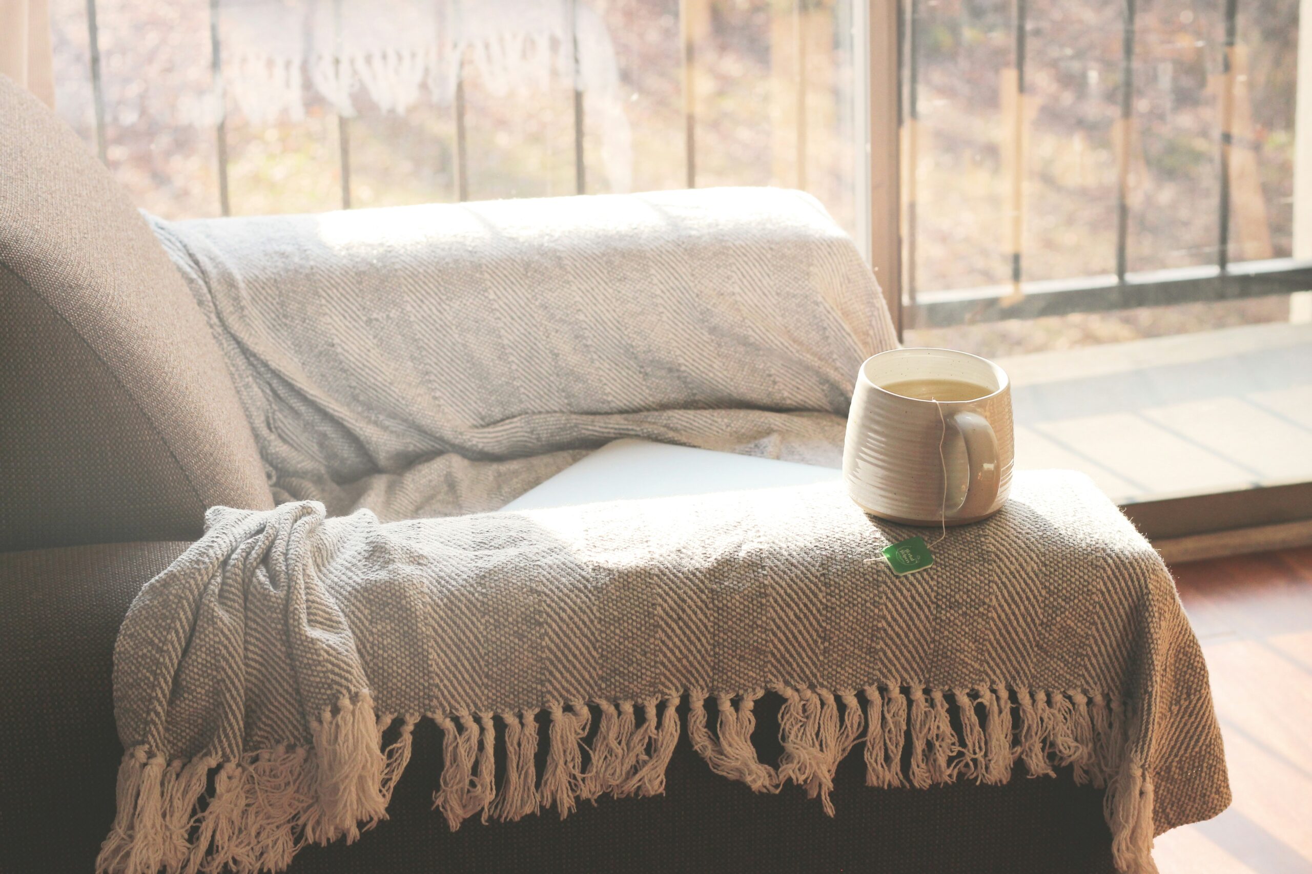 A quiet living room with a soft blanket in warm sunlight, representing anticipatory grief and loving someone who is still physically here.