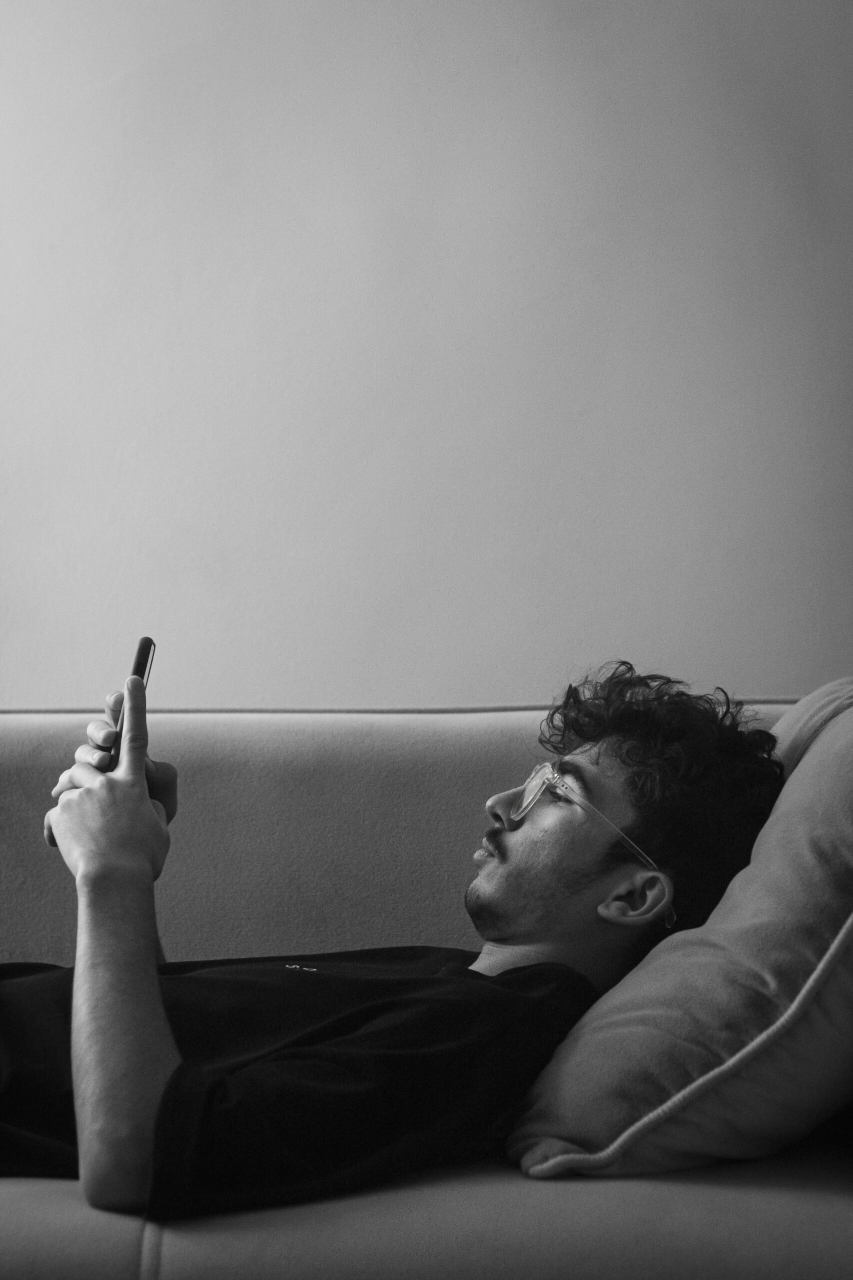 Rest Guilt and Phone Availability A person lying down while holding a phone, representing rest guilt, boundaries, and the pressure to stay available.