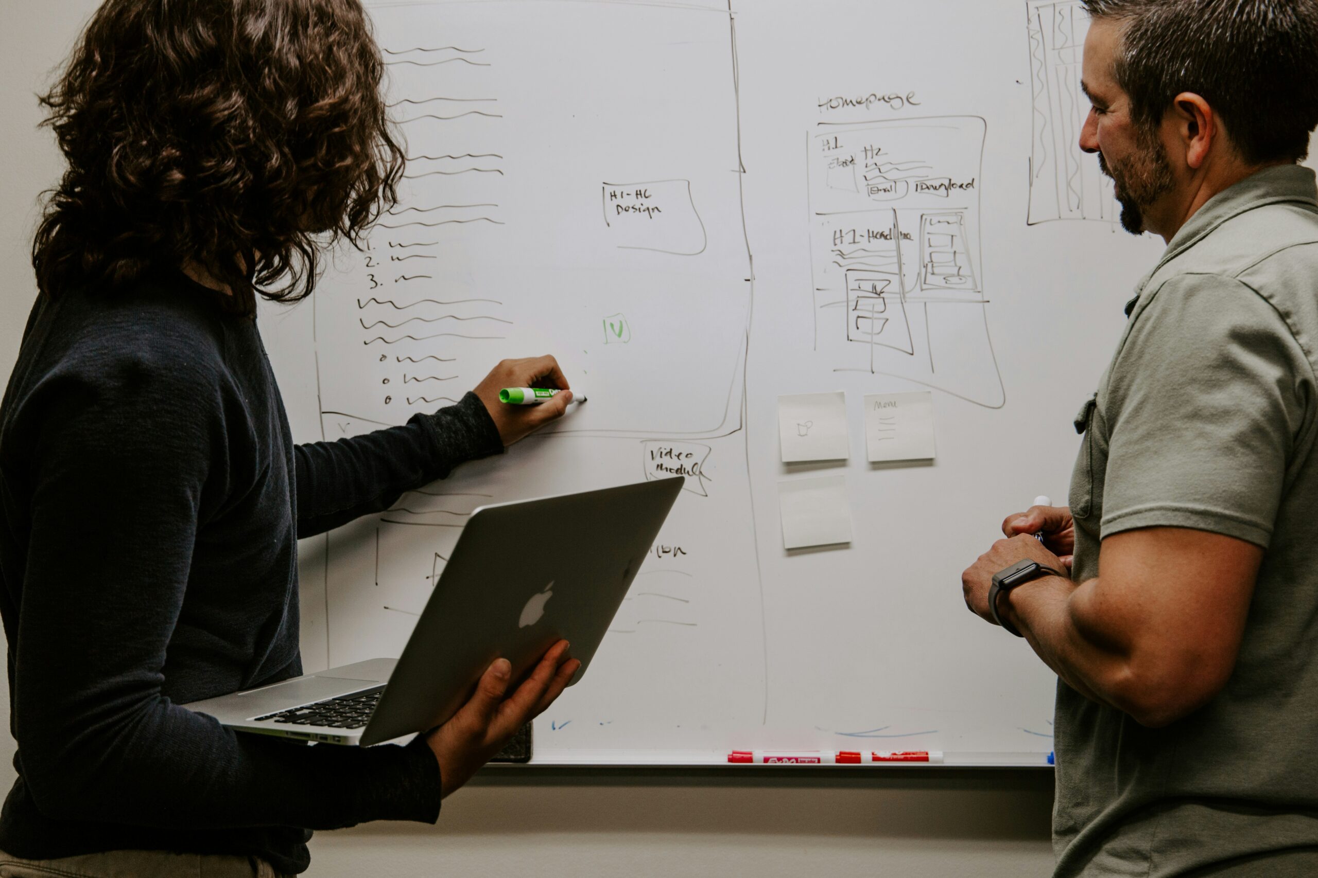 Two people planning together on a whiteboard with a laptop, illustrating collaboration, organization, and executive functioning support.